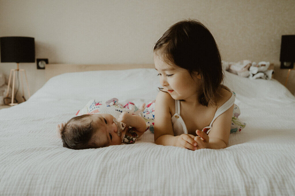 Un grand frère et une grande sœur avec le nouveau-né, à la maison
